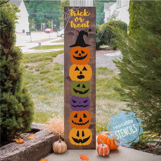 Halloween decor sign with colorful stacked pumpkin faces and trick or treat text, perfect for autumn display.