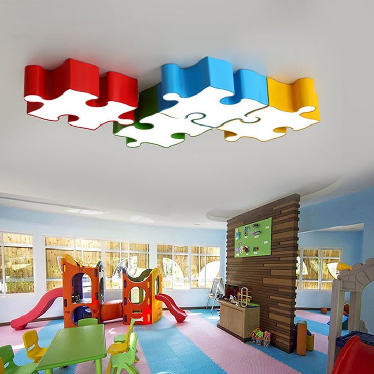 Colorful puzzle piece lights in a bright, fun children's playroom with slides and activity stations.