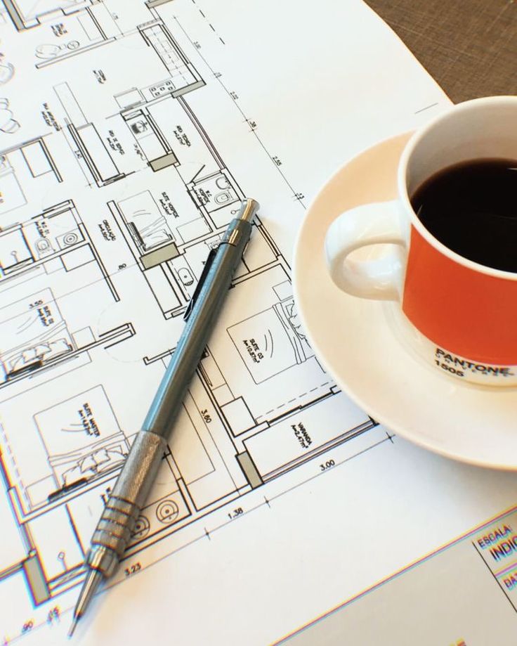 Architectural blueprint with pencil and coffee cup on table, symbolizing design creativity and planning.