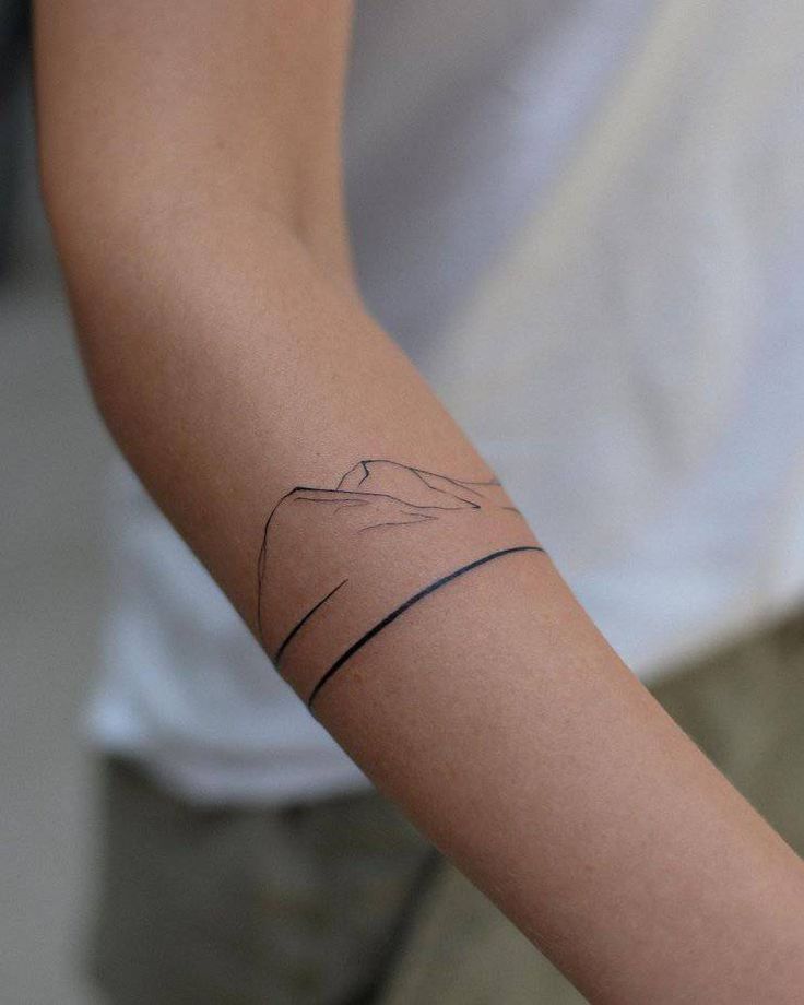 Minimalist mountain line tattoo on forearm, showcasing simple black ink design.