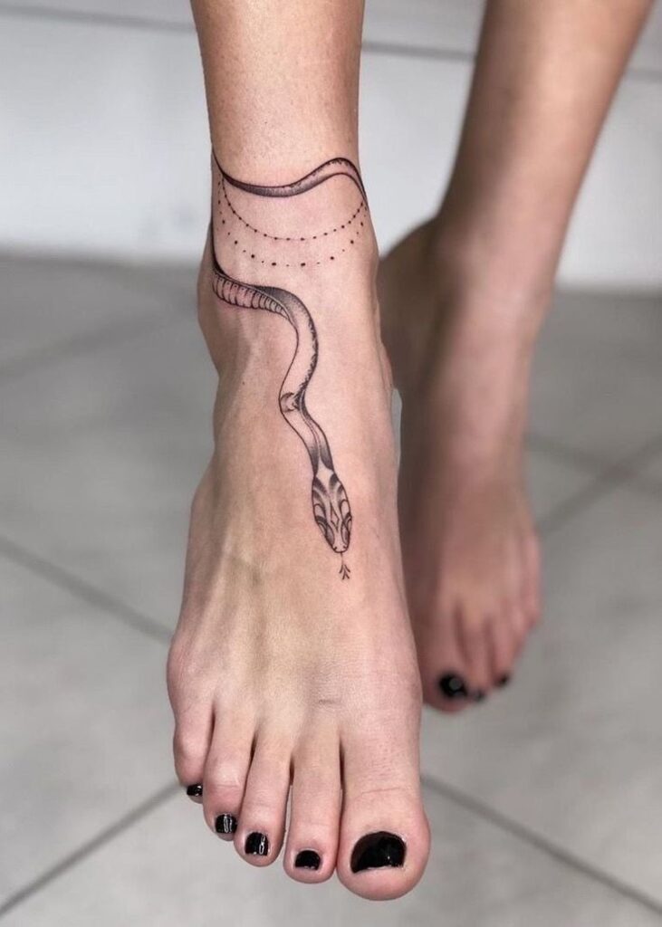 Minimalist snake tattoo on foot with black nail polish.