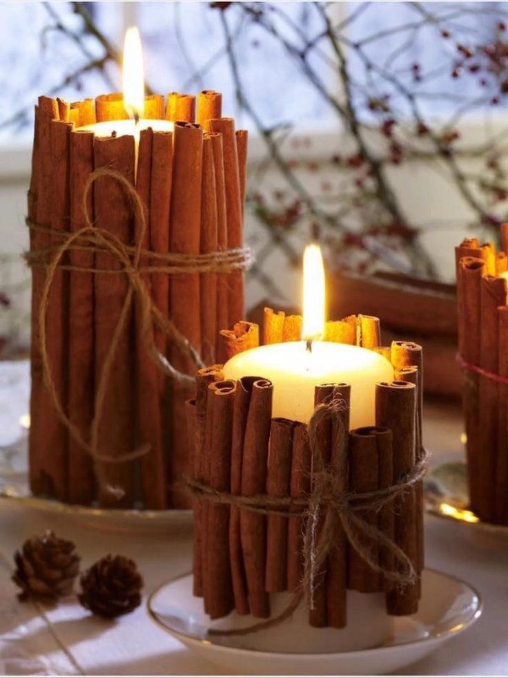 Cozy cinnamon stick candles lit on a white plate, perfect for a warm, rustic ambiance in winter decor.