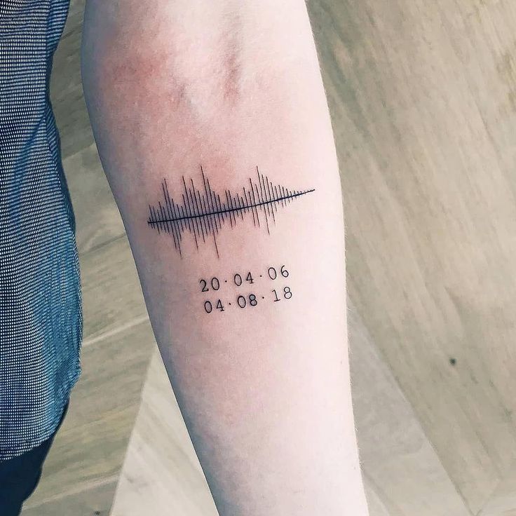 Soundwave tattoo with significant dates on arm, minimalist design on light skin.