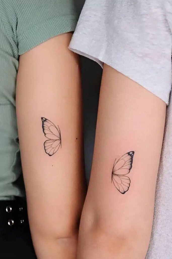 Matching butterfly tattoos on two arms, symbolizing friendship or connection, minimalist ink art.