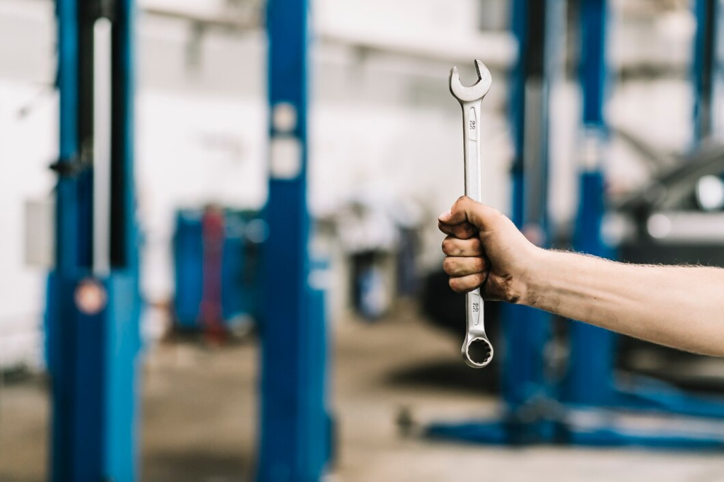 Mechanic holding a wrench in an auto repair shop, symbolizing professional car maintenance and repair services.