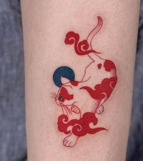 Red and white cat tattoo with abstract design, featuring a blue circle on a person's arm.