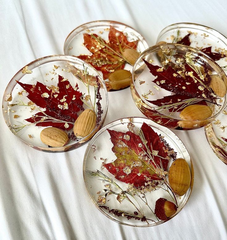 Handcrafted resin coasters with pressed red leaves, gold flakes, and almonds on a white background. Perfect for autumn decor.