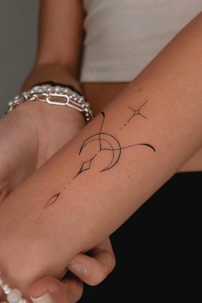 Minimalist moon and star tattoo design on arm, with delicate lines and geometric shapes.