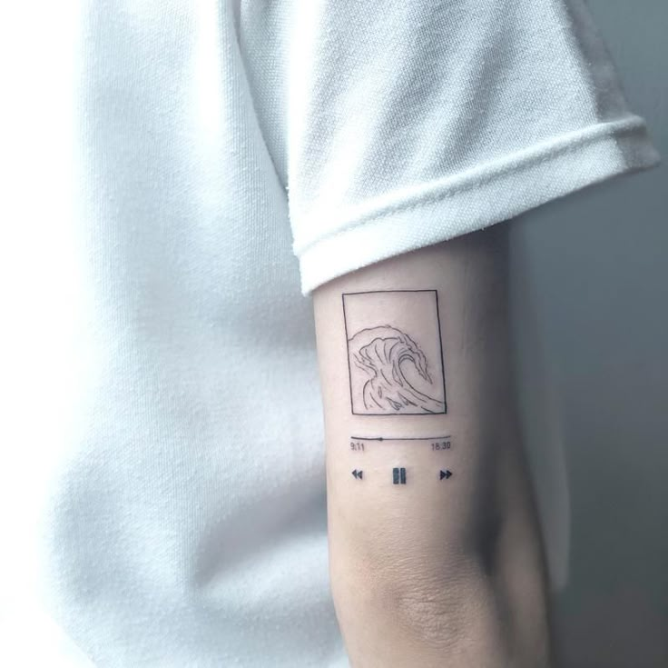 Minimalist wave tattoo with music player design on forearm, against a white shirt backdrop.