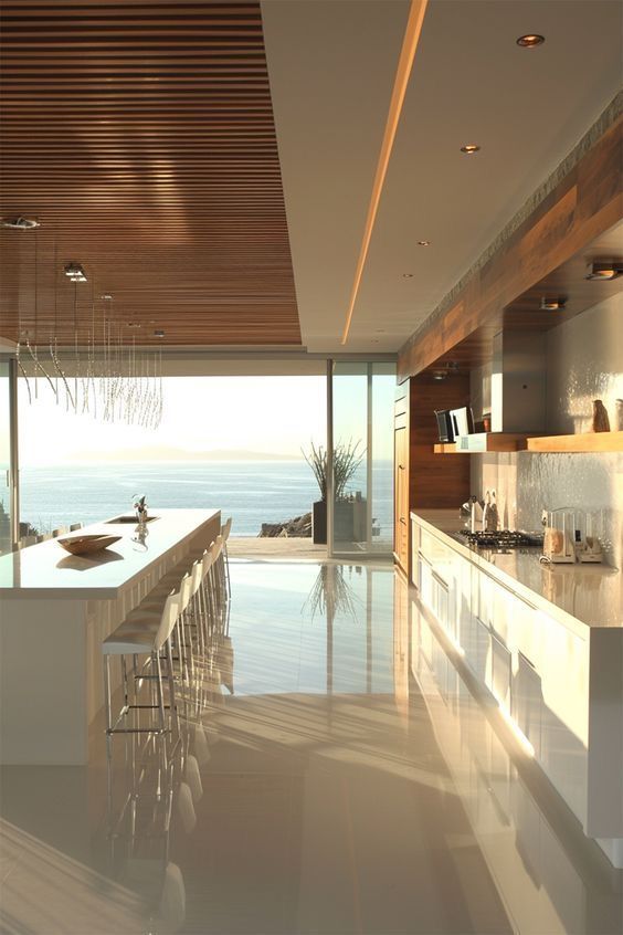 Modern kitchen with ocean view, sleek white countertops, and wooden accents. Sunlit, minimalist design.