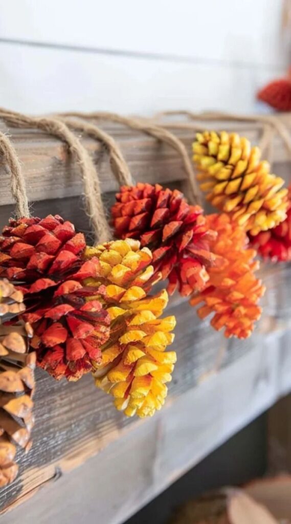 Colorful pine cone garland with autumn hues, hanging on rustic wooden background.