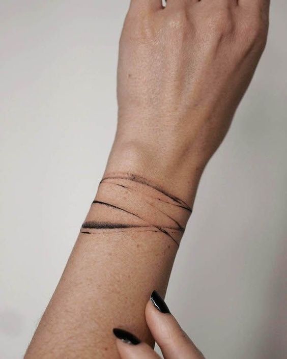 Minimalist black line tattoo on a wrist, showcasing abstract design with a modern, artistic style.