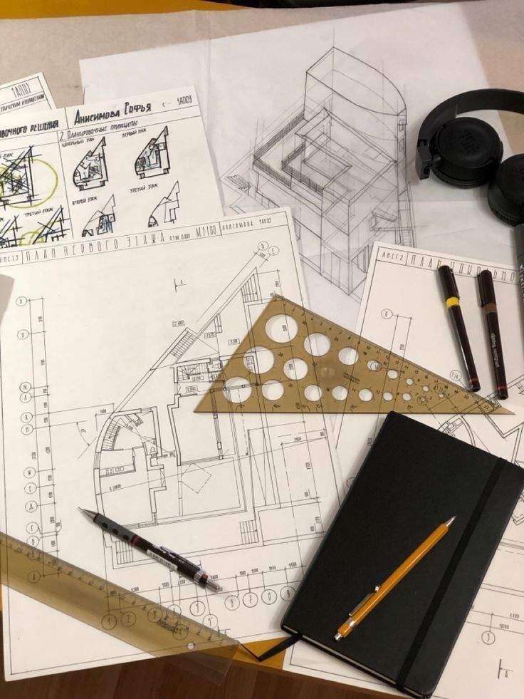 Architectural blueprints with drawing tools and notebook on desk.