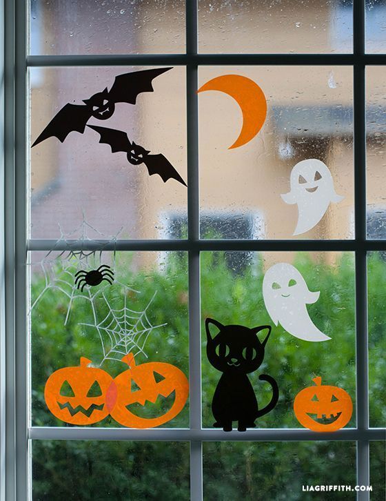 Halloween window decorations with bats, ghosts, pumpkins, spider webs, and a black cat.