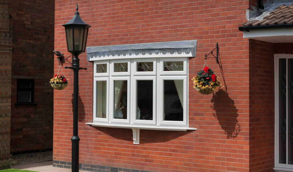 Brick house with bay window, hanging flower baskets, and classic black lamp post, creating a charming exterior view.