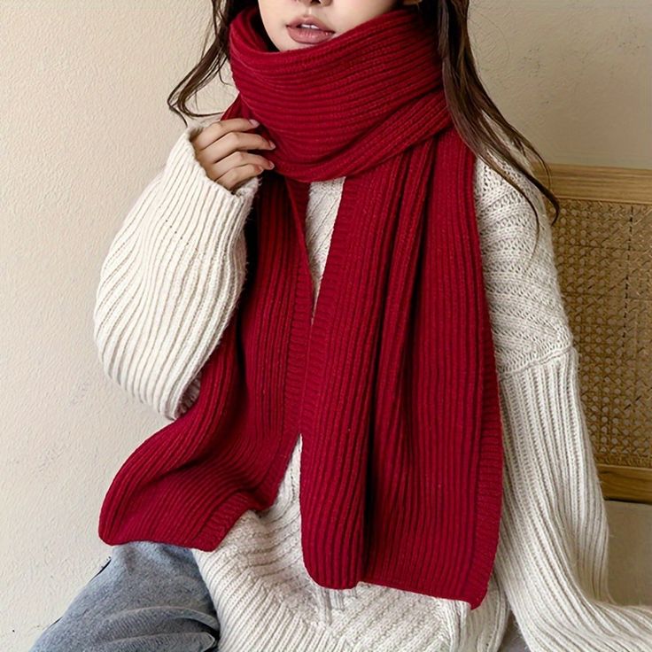 Woman wearing a cozy red scarf and white sweater, showcasing winter fashion elegance.