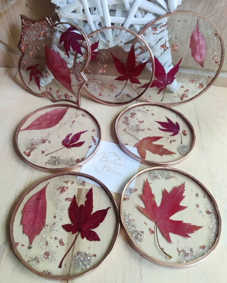 Round resin coasters with embedded autumn leaves and gold flakes, displayed on a wooden surface.