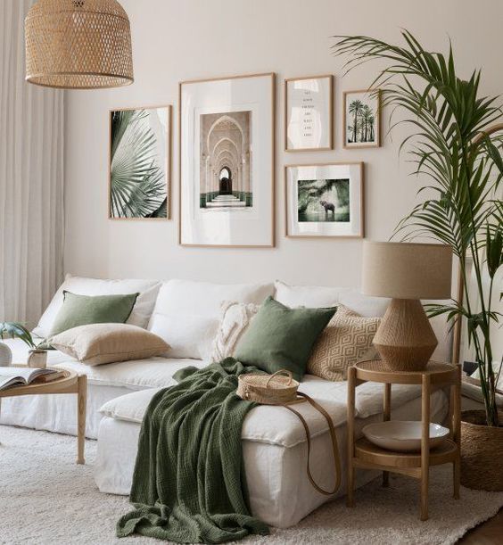 Cozy living room with green accents, white sofa, framed wall art, and lush indoor plants. Natural light and earthy tones.