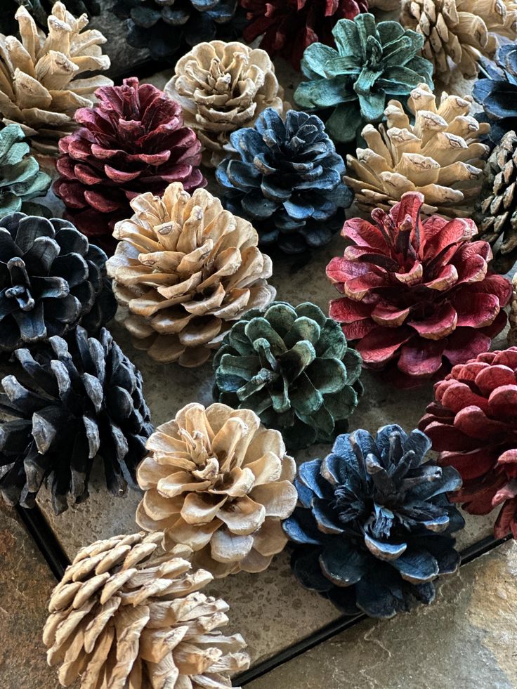 Colorful painted pine cones arranged on a rustic surface for a festive decoration.