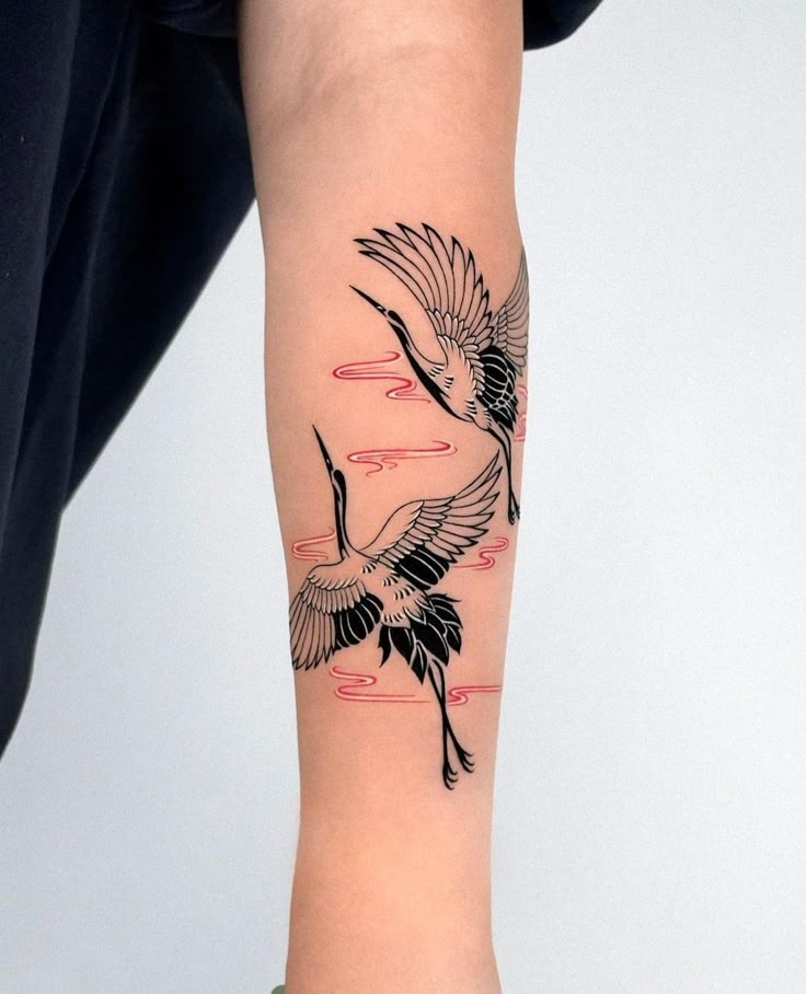 Elegant crane tattoo with red accents on forearm, showcasing artistic bird design and clean lines.