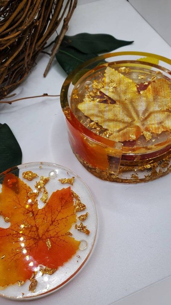 Decorative resin coasters featuring fall leaves and gold flakes, ideal for autumn-themed home decor.