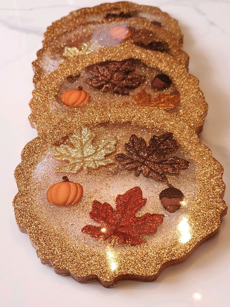 Glittery autumn-themed coasters with leaves, acorns, and pumpkins for festive home decor.