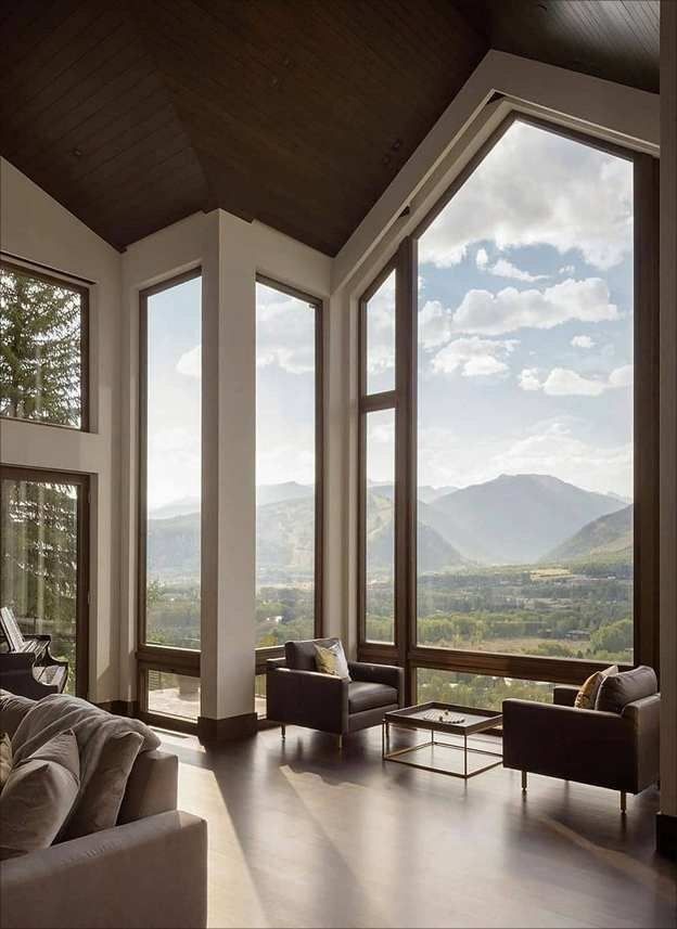 Spacious living room with floor-to-ceiling windows offering a stunning mountain view. Modern furniture and natural light.