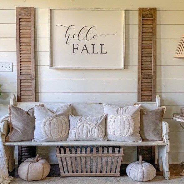 Cozy fall-themed living room with pumpkin pillows, rustic bench, and Hello Fall sign.