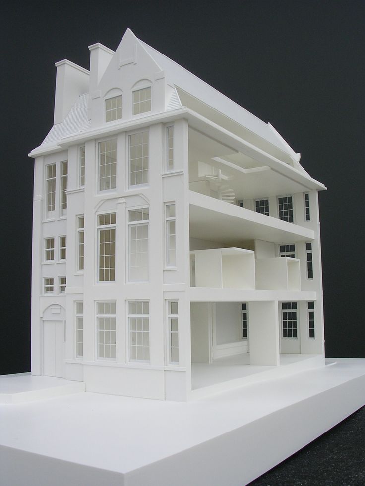 Architectural model of a multi-story white building with open sections, showcasing modern design and large windows.