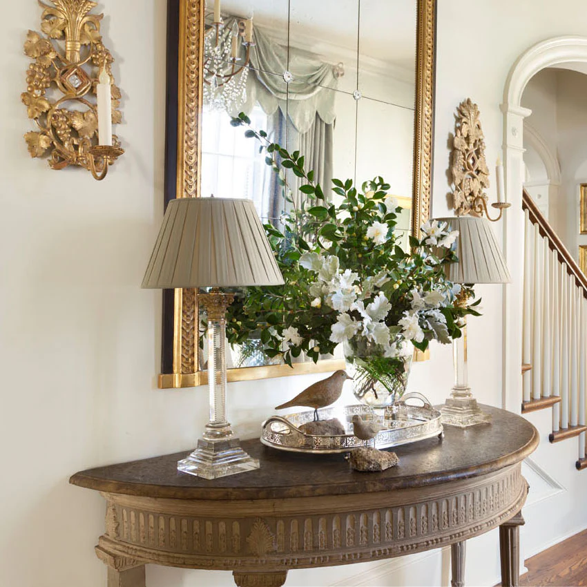 Elegant hallway table with decorative lamps, mirror, and floral arrangement, creating a classic and inviting entryway.