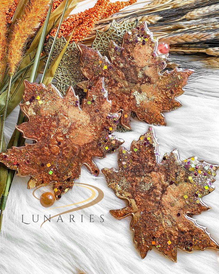 Decorative resin maple leaves with autumn colors and sparkles, styled with seasonal accents on a white background.