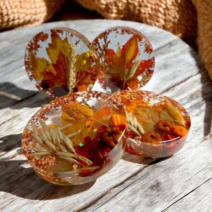 Handcrafted resin coasters with autumn leaves and flowers on wooden table, adding seasonal charm to home decor.