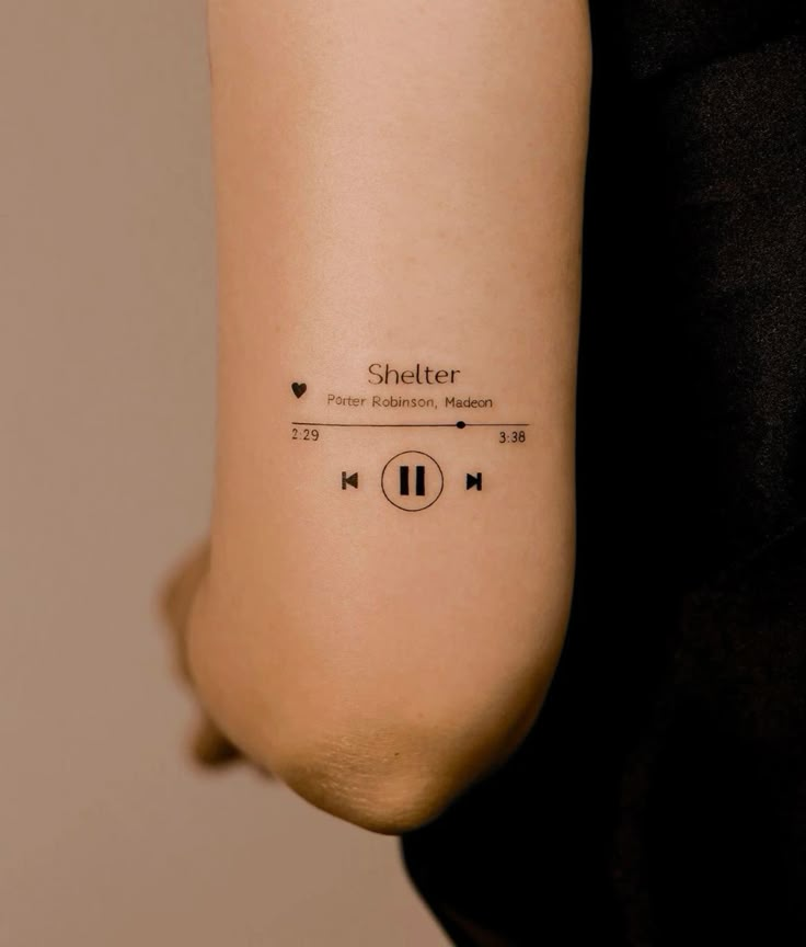 Tattoo of music player on arm featuring Shelter with controls and timer, minimalist design, black ink.