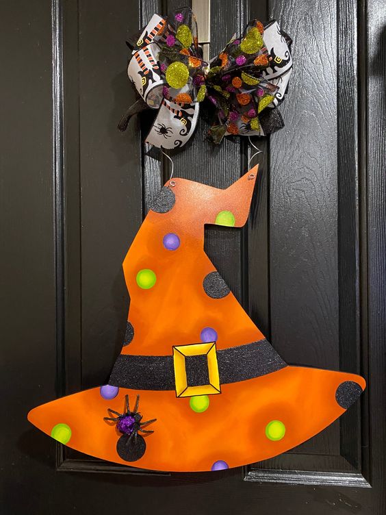 Bright orange witch hat door decoration with a colorful bow and polka dots, perfect for Halloween.