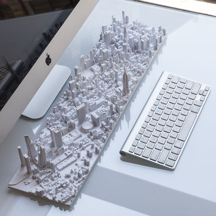 3D printed city model on desk with computer and keyboard, showcasing intricate urban architecture details.