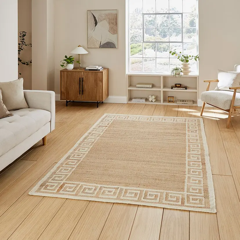 Cozy living room with natural light, featuring a beige rug, modern furniture, and wooden flooring.