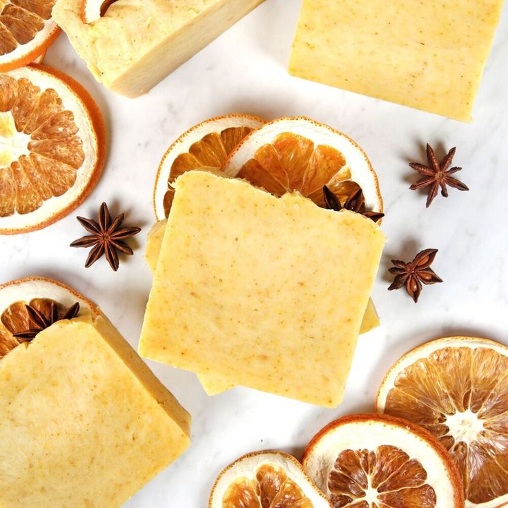 Homemade orange spice soap bars with dried orange slices and star anise on a marble surface.