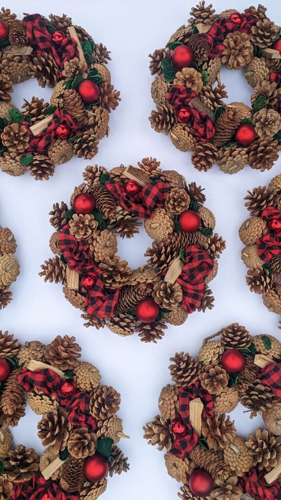 Festive pine cone wreaths with red ornaments and plaid ribbons on a white background. Perfect holiday decoration.