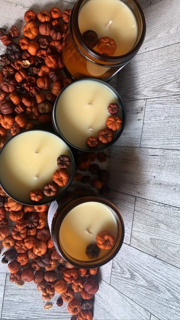 Cozy autumn candles with mini pumpkins on a rustic wooden floor, creating a warm fall ambiance.