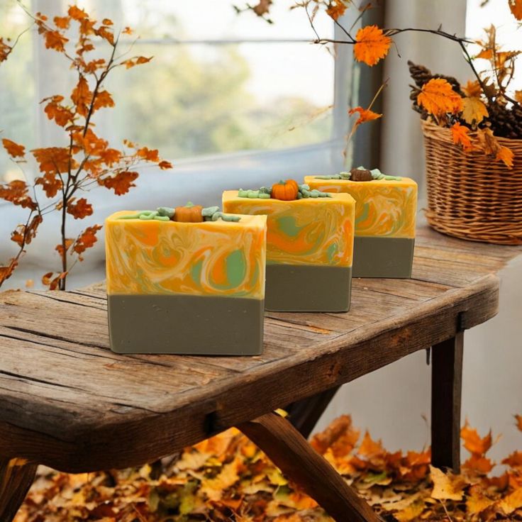 Handcrafted autumn-themed soap bars on a wooden table surrounded by fall leaves and decor.