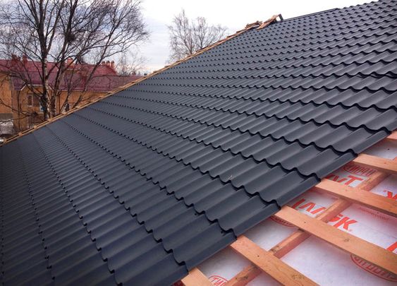 New black metal roof installation on a wooden frame, showcasing modern and durable roofing materials.