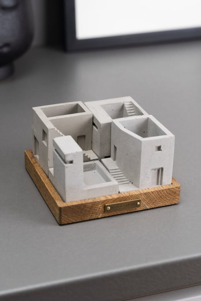 Miniature concrete building model on wooden base, showcasing modern architectural design.