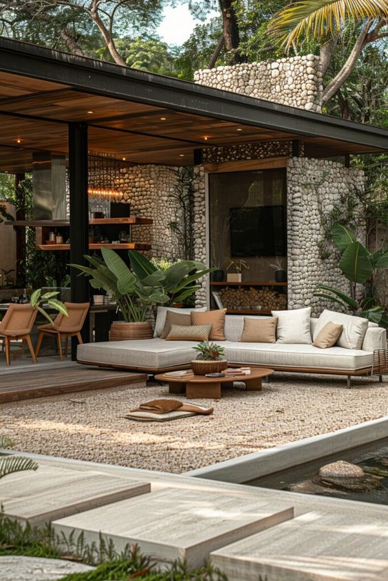 Modern outdoor patio with stone walls, stylish furniture, and lush greenery; perfect for relaxation and entertaining.