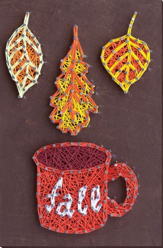 String art of fall leaves with a red mug on brown background. Cozy autumn vibes with colorful thread.