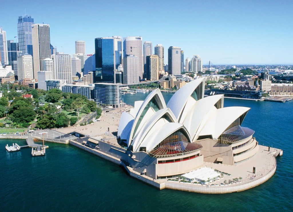 Sydney Opera House and city skyline, aerial view over Sydney Harbour. Iconic architecture and urban landscape.