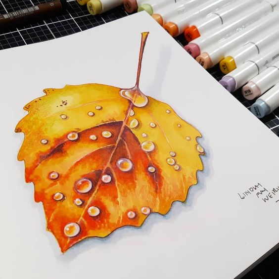 Colorful autumn leaf drawing with water droplets, surrounded by an array of Copic markers on a table.