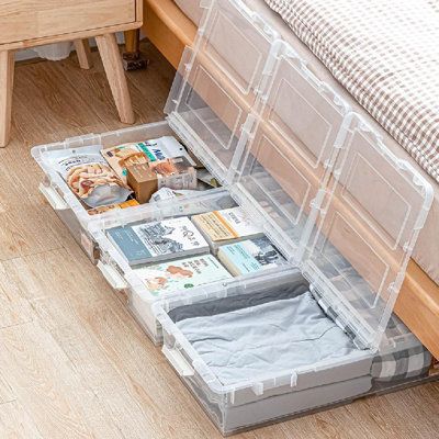 Clear storage containers under a bed filled with books and items, maximizing space with organized under-bed storage solutions.