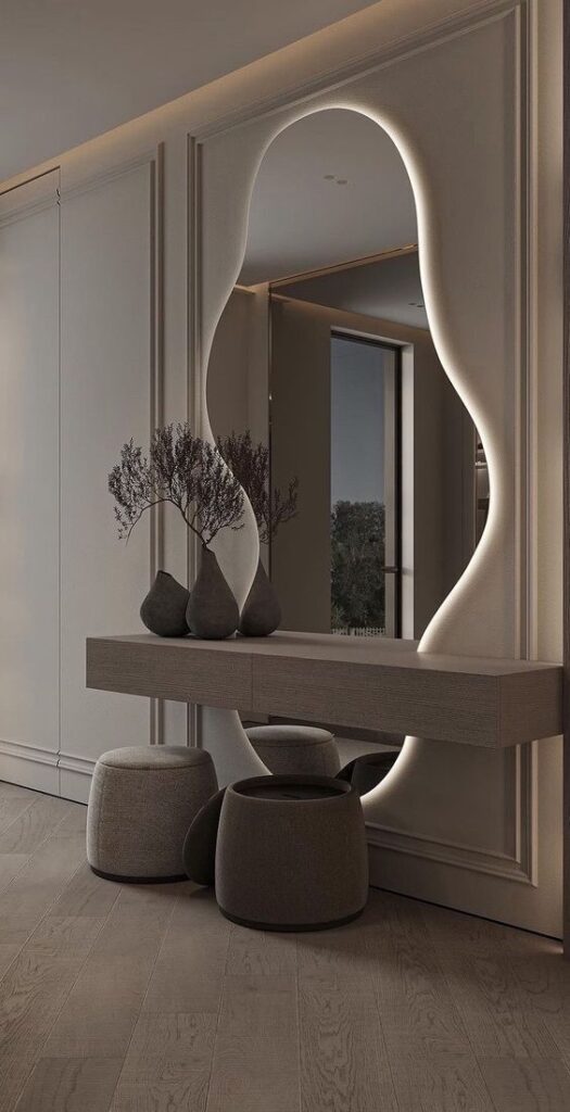 Modern hallway with unique mirror, wooden console, vases, and round poufs enhancing interior design elegance.