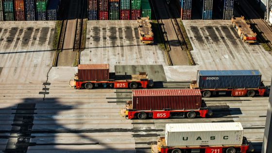 Automated trucks transporting shipping containers at a busy port terminal.