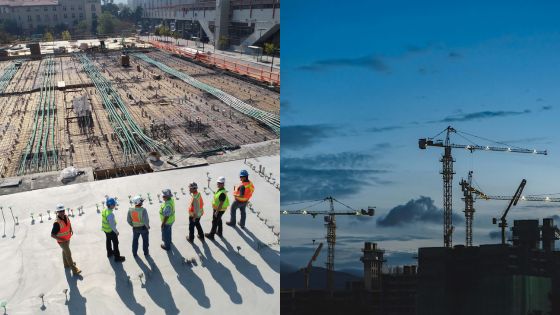 Construction site with workers discussing plans and cranes silhouetted against the sky.